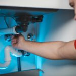 Installateur repariert eine Wasserleitung unter dem Waschbecken
