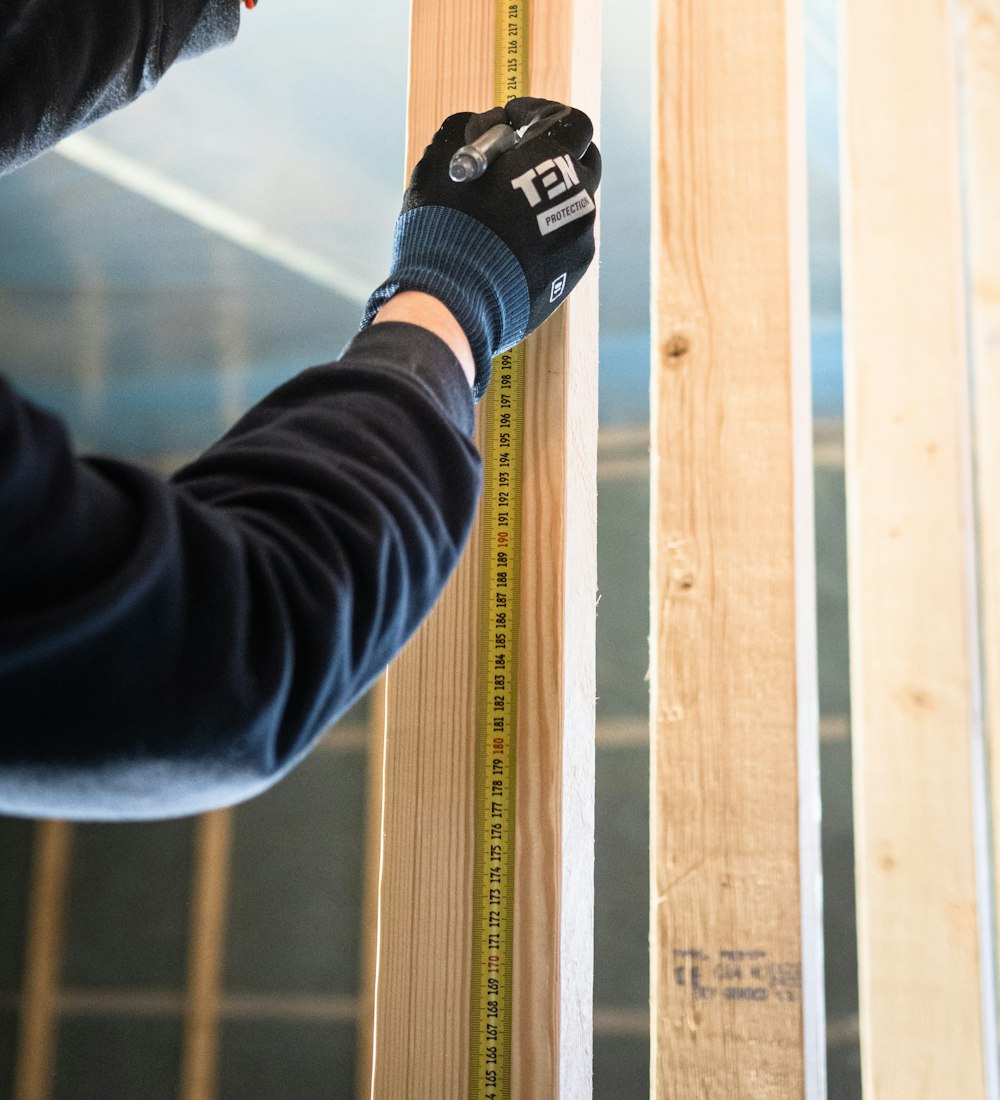 Handwerker misst Holzbalken beim Innenausbau – Fachbetriebe finden auf MyMeister