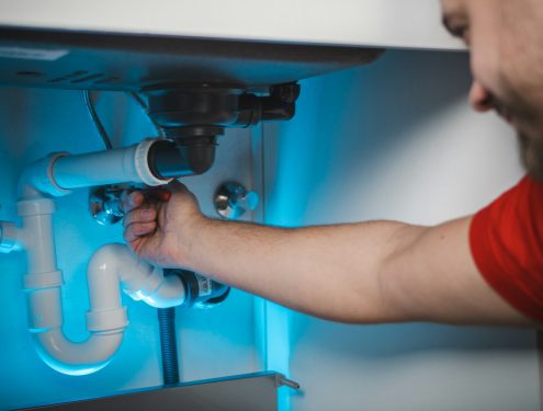 Installateur repariert eine Wasserleitung unter dem Waschbecken